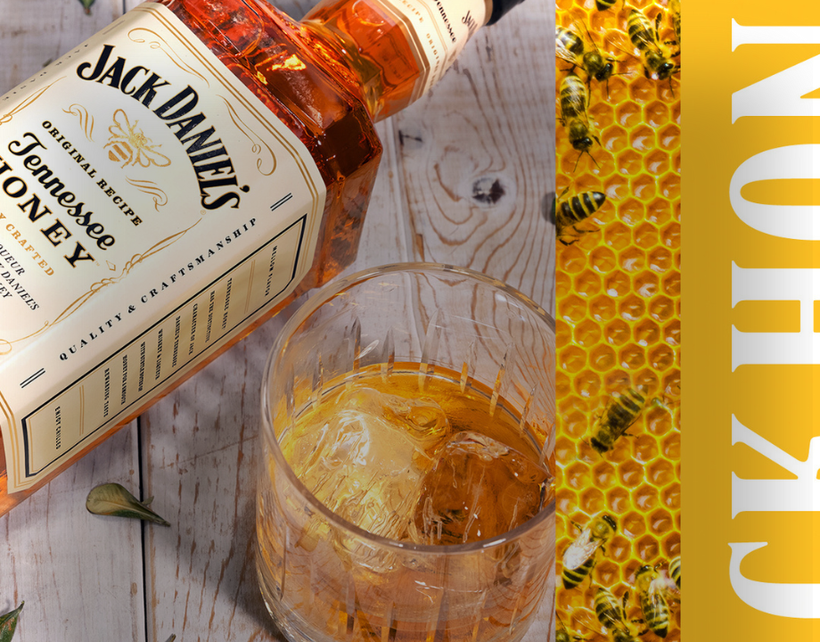 Jack Daniel's Honey Flasche neben Whiskey Glas und Honigwabe mit Bienen drauf