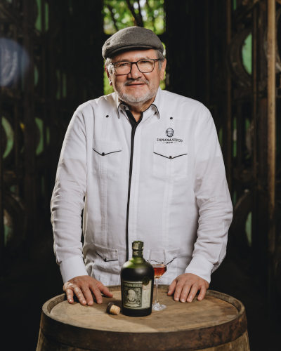 Mann steht hinterm Fass mit Diplomatico Flasche und eingeschenktem Glass