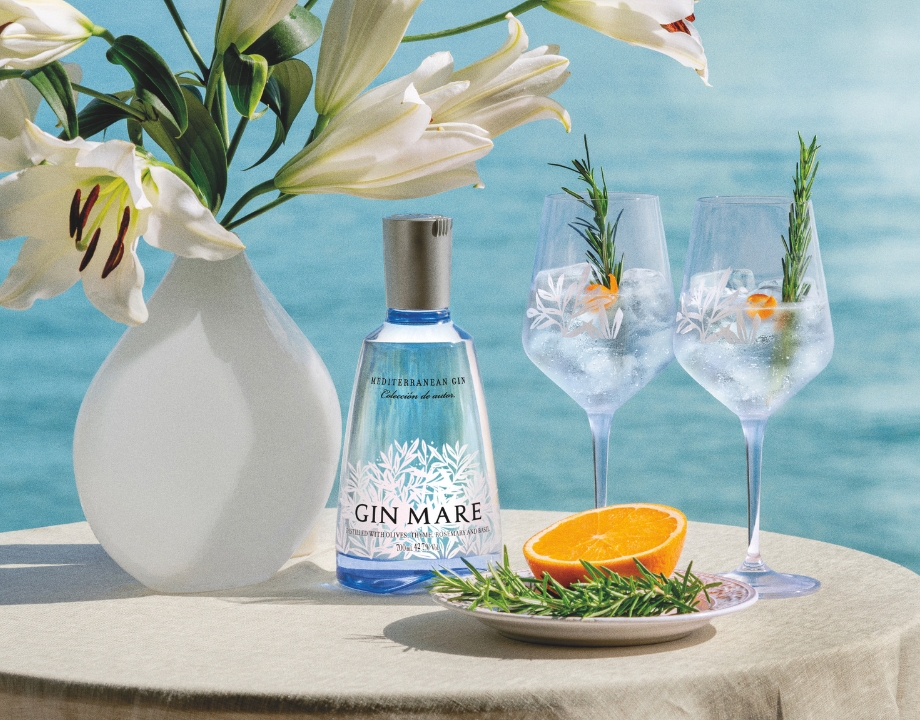 Gin Mare Flasche und Gläser auf Tisch mit Meerblick.