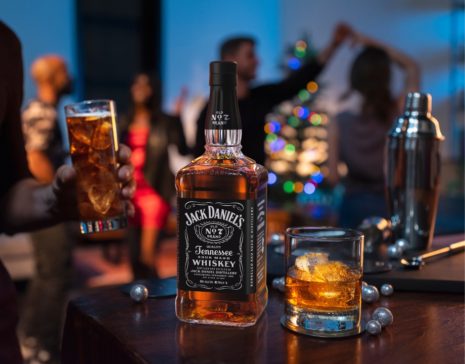 Jack Daniel’s Flasche und Glas in weihnachtlicher Party-Atmosphäre.